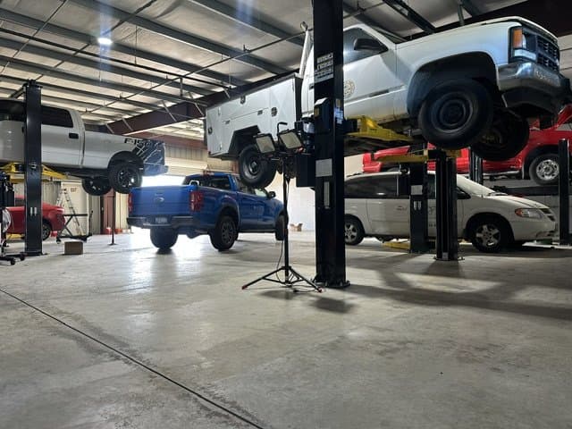 Pickup trucks raised on lifts inside an All Automatic Transmission service bay