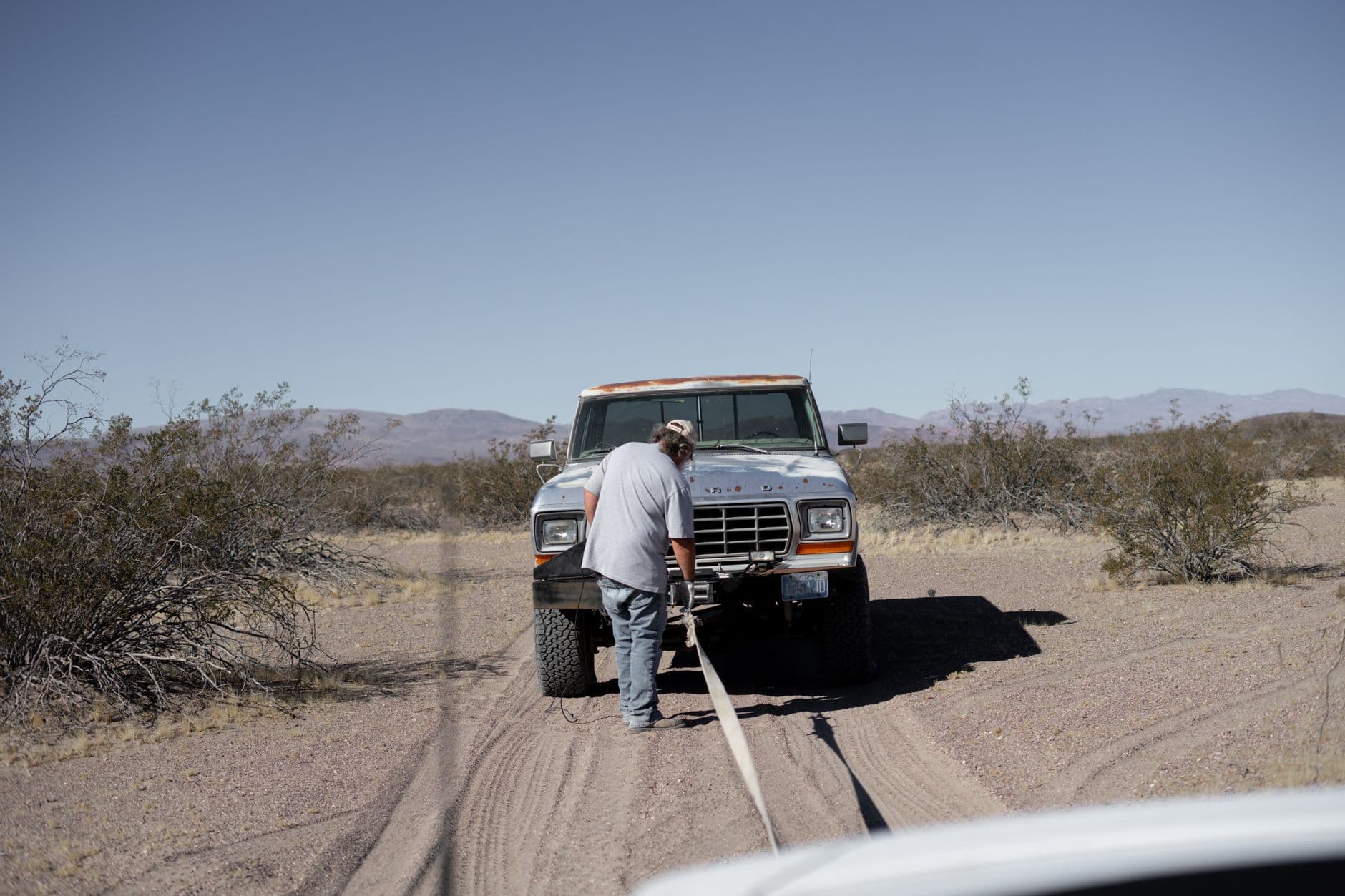 A pickup being towed on a desert road after a breakdown